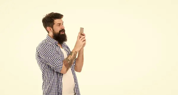 man blogger smile with phone isolated on white background. blogger man in studio. photo of man blogger. bearded man blogger making photo with copy space.