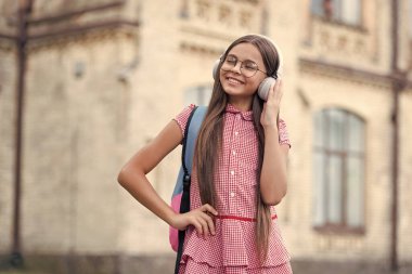 Genç kız internetten eğitim görüyor. Genç kız internetten kulaklık eğitimi alıyor. Genç kız açık havada eğitim görüyor. Genç kızın fotoğrafı internetten eğitim görüyor..