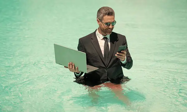 business manager work in summer with phone. photo of business manager wearing suit work in summer pool. business manager work in summer. business manager work in summer at swimming pool.