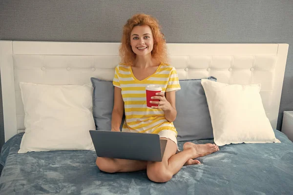 happy girl freelancer with coffee at home chat on laptop. freelancer girl work at home. home work for freelancer. girl in bed with laptop.