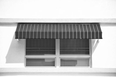 Binanın penceresinde güneş gözlüğü var. Çizgili pencere güneşliği. Dışarıdaki pencere perdeleri. pencere güneş ışığının fotoğrafı.