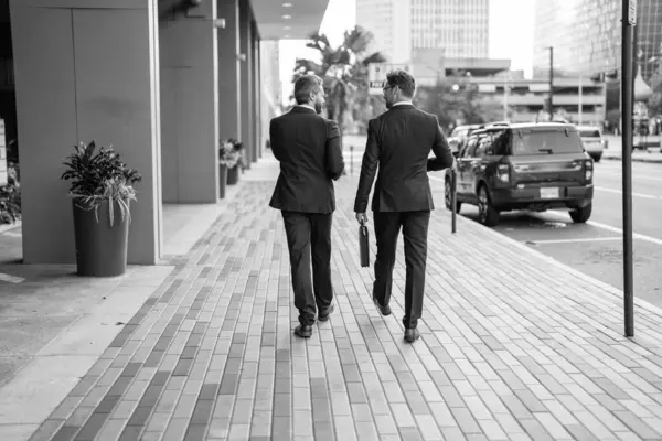business men coworker walk. business men coworker outdoor. business men coworker in the street. photo of business men coworker wearing suit.