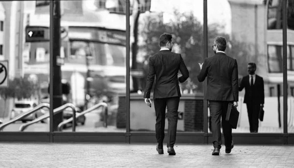back view of business men coworker in the street, banner. photo of business men coworker wearing suit. business men coworker walking. business men coworker outdoor.