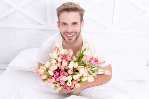 happy romantic man with march tulips flowers. romantic man with tulips for 8 march. photo of romantic man with march tulips bouquet. romantic man with march tulips.