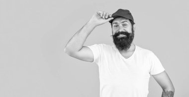 Şapkalı, reklamlı, sakallı teslimatçının fotoğrafı. Sarıda izole edilmiş sakallı teslimatçı. Stüdyodaki sakallı teslimatçı. Arka planda sakallı teslimatçı var..