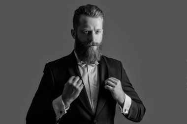 Smokinli beyaz sakallı adam gri arka planda izole edilmiş. Smokin giymiş bir adamın stüdyosu. Zarif smokin giyen bir adam. Smokin modası.