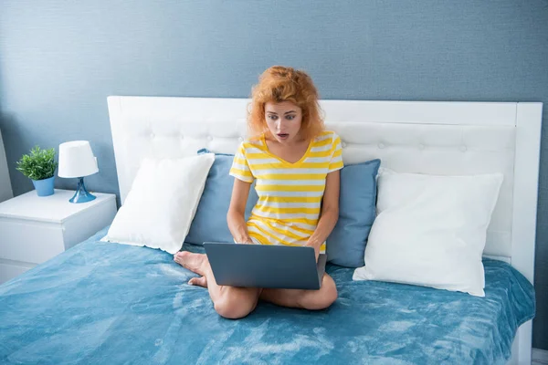 shocked woman blogger work at home on laptop. blogger woman work at home. home work for blogger. woman in bed with laptop.