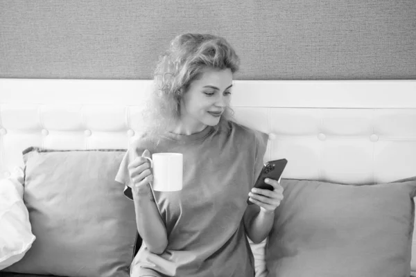 woman smile with coffee chat on phone. woman chat at home with phone. phone chat at home of woman.