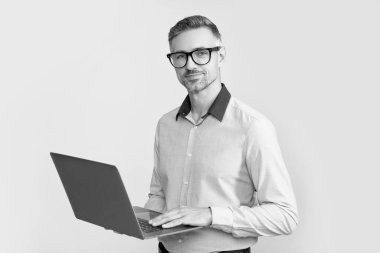 mature boss in eyeglasses working on computer on grey background.