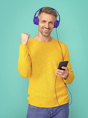 Stüdyoda başarılı bir adamın mp3 çalma listesi var. Arka planda mp3 açık çalma listesi var. mp3 'te açık çalma listesi olan bir adamın fotoğrafı. MP3 üzerindeki adam açık çalma listesi mavi üzerine izole edildi.