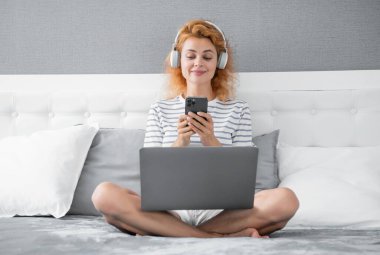 positive woman shopping online on phone. woman has shopping online with phone chat at home. online shopping of woman in headphones.