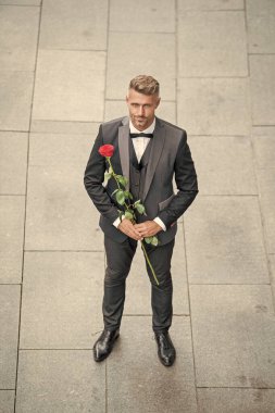 Nişan tarihi. Olgun smokinli adam nişanı kutluyor. Nişan için gül hediyeli bir adam.