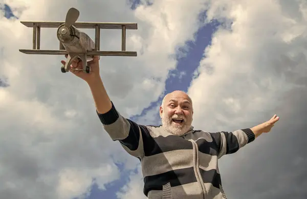 happiness of senior man on sky background. senior man at retirement. senior retired man with toy plane outdoor.