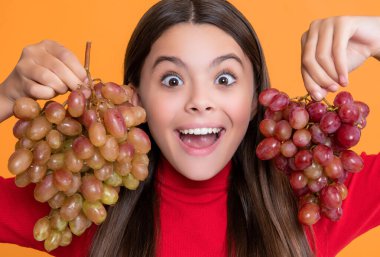 Şaşkın kızın sarı arka planda üzüm tutmasına sevindim..