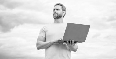 Gökyüzü arka planında dizüstü bilgisayarda çalışan serbest çalışan.