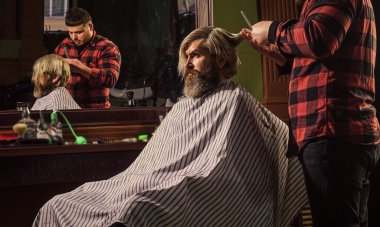 Yaşam tarzı. Usta berber saç stilini ve saç stilini kurutma makinesiyle yapıyor. Berber dükkanı kavramı. Genç hippi sakallı adam berber dükkanında saçını kesiyor. Profesyonel kuaför işi..