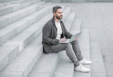 Bilgisayarlı neşeli adamın blog 'u. Blog yazma konsepti. Adam dışarıda dizüstü bilgisayarda blog yazıyor. Bilgisayarlı adam çevrimiçi blog yazıyor.