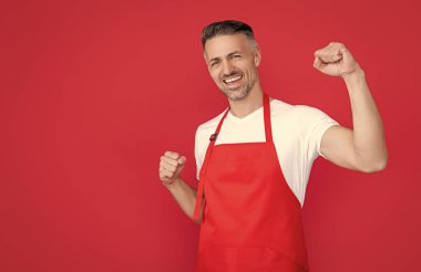 mature barman in apron on red background.