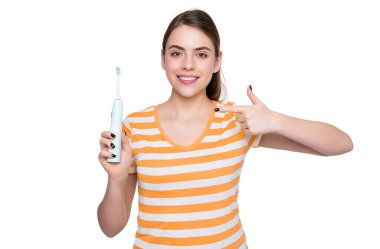 Neşeli genç kadın, beyaz arka planda izole edilmiş elektrikli diş fırçasını işaret ediyor..