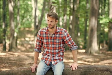 young handsome guy in checkered shirt sitting outdoor.