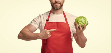 Önlüklü bir adam, beyaza izole edilmiş lahana sebzeli. işaret parmağı.