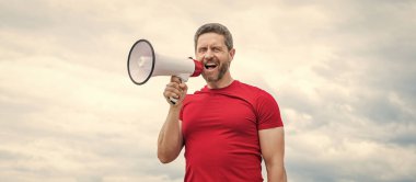 man salesperson in red shirt shout in loudspeaker on sky background.
