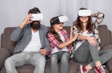 Çocuklu neşeli ebeveynler evde, sanal gerçeklikte, VR gözlükleriyle vakit geçiriyorlar..