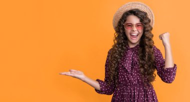 Hasır şapkalı, güneş gözlüklü, uzun kıvırcık saçlı gülümseyen bir çocuk. Boşluğu kopyala.