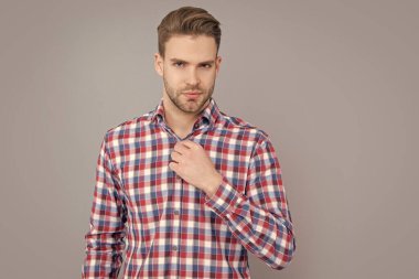 Gri arka planda kareli gömlekli yakışıklı bir adam izole edilmiş. Sıradan giyinen bir adam. Stüdyo fotoğrafı. Kafkasyalı adamın sakalı var..