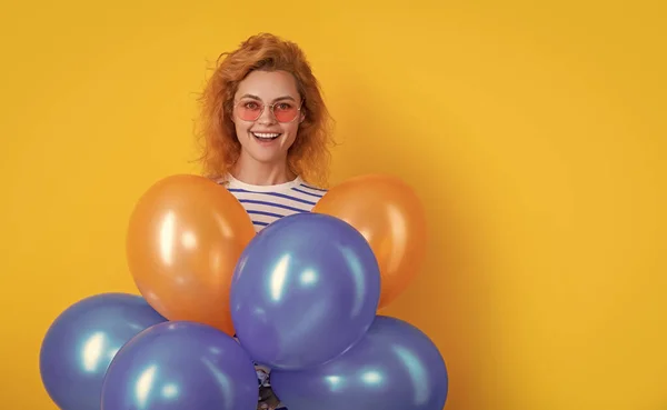 party woman with balloon in sunglasses. cheerful woman hold party balloons in studio. woman with balloon for party isolated on yellow background.