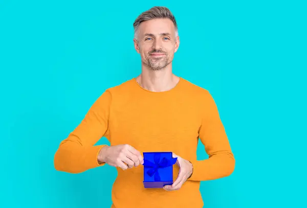 cheerful man shopper with present in studio. man shopper with present on background. photo of man shopper with present. man shopper with present isolated on blue.