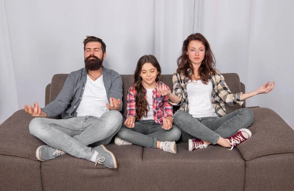 calm yoga meditation. family day. friendship. father mother and child on sofa. friendly family having fun. happy parents with kid girl at home. mom dad and daughter love relax together.