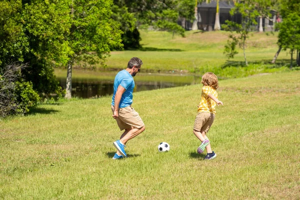 Father and child son teaming up outdoor. Father dad and son enjoying outdoor activities together. Outdoor adventures between father and son. Active father son playing football in summer. family fun.