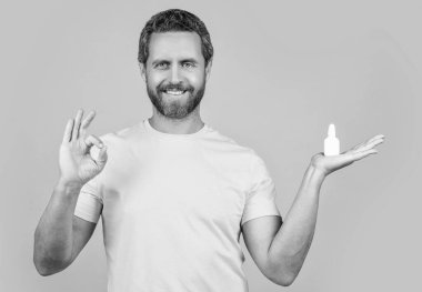 Burun tıbbı olan adam sarıda izole edilmiş, tamam mı? Stüdyoda burun tıbbı olan bir adam. Burun ilacı damlaları olan bir adamın fotoğrafı..