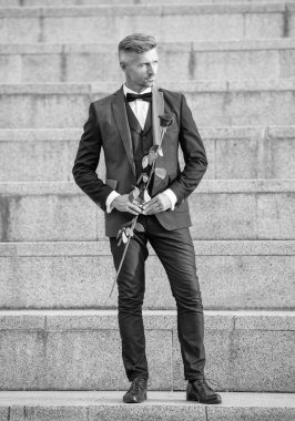 Sevgililer Günü konsepti. Sevgililer günü gülü olan karizmatik siyah smokinli adam. Sevgililer Günü için çiçek hediyesi.