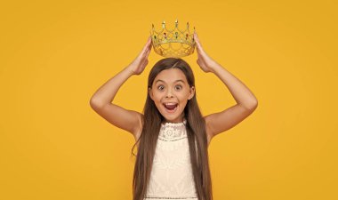 amazed teen girl in crown on yellow background.