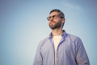 pensive thoughtful man standing peaceful. pensive man in glasses outdoor. pensive man on sky background.