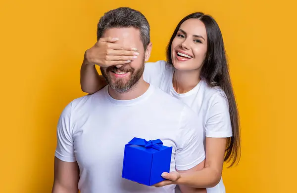 Boyfriend receiving present from girlfriend. Valentines day couple. Couple in love. Mans day gift. Loving woman giving present for Valentines day. Gift box to surprised man. Happy birthday.
