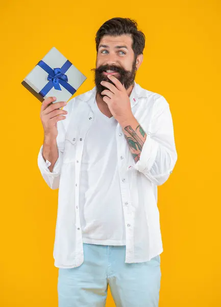 smiling caucasian birthday man with purchase isolated on yellow. birthday man with purchase in studio. birthday man with purchase on background. photo of birthday man with purchase box.