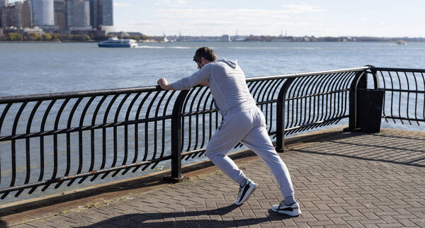 Sportsman stretching his muscles and preparing for workout routine of athlete outdoor in New York city.