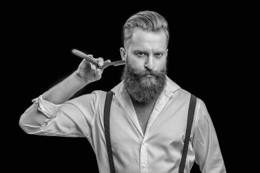 Retro tıraş bıçağı olan berber adam. Arka planda berberin fotoğrafı var. Berber adam siyahlar içinde izole edilmiş. Stüdyoda berber..