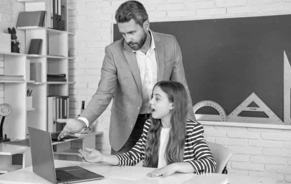 stock image amazed child with teacher in classroom use laptop.