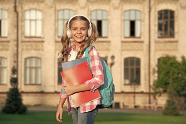 Happy teen girl back to school outdoors, music.