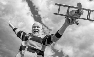 Kıdemli adam gökyüzü geçmişinde iyi eğlenceler. Emeklilikteki son sınıf. Dışarıda oyuncak uçağı olan yaşlı emekli bir adam..