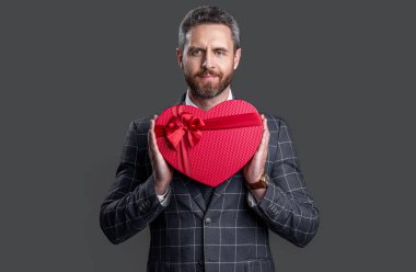 businessman with present for valentines day isolated on red. businessman hold valentines day present in studio. businessman with valentines day present. businessman holding valentines day present box.