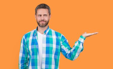 photo of caucasian guy wear checkered shirt presenting copy space. caucasian guy wearing casual style. bearded caucasian guy in casual shirt isolated on yellow background. caucasian casual guy