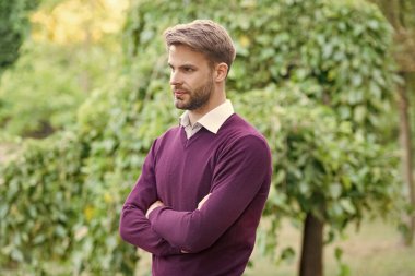 Havalı giyinen yakışıklı genç adam ellerini açık havada çapraz yaptı..