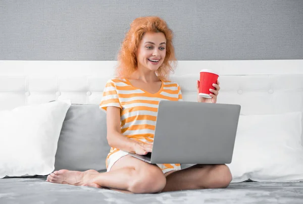 cheerful woman freelancer with coffee work at home on laptop. freelancer woman work at home. home work for freelancer. woman in bed with laptop.
