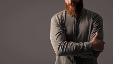 Traşsız adamın stüdyo görüntüsü. Bıyık ve sakal bakımı. Yakışıklı, sakallı ve bıyıklı. Gri arka planda sakallı ve bıyıklı traşsız bir adam..