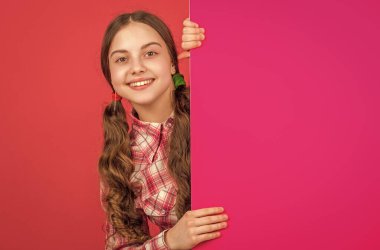 Gülümseyen genç kız reklam için fotokopi alanı olan boş pembe kağıdın arkasında..